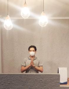 Um homem mascarado a rezar numa sala com luzes em Nyenyak Senayan Benhil em Jakarta
