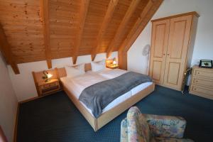 a bedroom with a large bed and a chair at Landhotel Steigerwaldhaus in Burghaslach