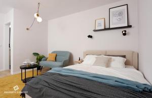 1 dormitorio con 1 cama y 1 silla azul en Brand new lovely studio close to Favorit metro station, en Bucarest
