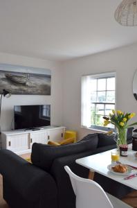 un soggiorno con divano nero e TV di The Old Fishermans Lookout a Falmouth
