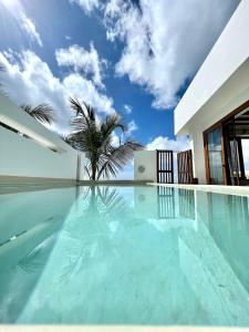 a swimming pool in a villa with a palm tree at Zanzibar Tiny Villa at La Villa De Victor in Matemwe