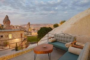 Lunar Cappadocia Hotel في غوريمِ: شرفة مع أريكة وطاولة وإطلالة