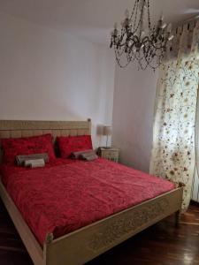 a bedroom with a large red bed with a chandelier at LA QUIETE TRA LE VIGNE Tuscany in Collesalvetti