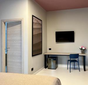 a bedroom with a desk and a tv on the wall at La Maison - Boutique Rooms in Sperlonga