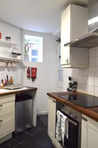 a kitchen with white cabinets and a stove top oven at Cockleshell Cottage in Falmouth