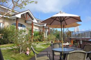 un patio con mesa y sombrilla en Starhome Cottage, en Renai