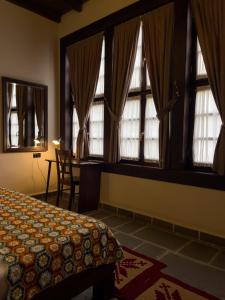 a bedroom with windows and a bed and a desk at Hotel Mangalemi in Berat