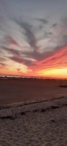 a sunset on a beach with a cloudy sky at Mimosas in Andernos-les-Bains