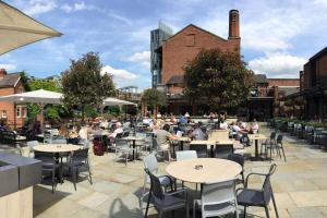 a group of people sitting at tables in a courtyard at Free parking- Central water-side apartment in Flixton