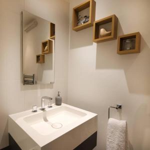 La salle de bains est pourvue d'un lavabo blanc et d'un miroir. dans l'établissement Free parking- Central water-side apartment, à Flixton