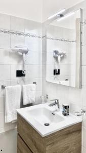 ein weißes Badezimmer mit einem Waschbecken und einem Spiegel in der Unterkunft La Maison - Boutique Rooms in Sperlonga