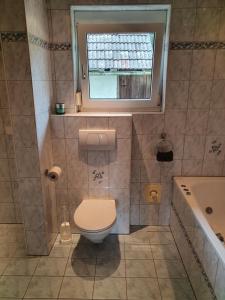 ein Bad mit einem WC, einem Fenster und einer Badewanne in der Unterkunft Ferienwohnung BeLu in Velden am Wörthersee