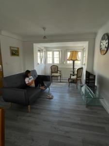 a woman sitting on a couch in a living room at Au Bon Vieux Port Maison de vacances Alsacienne à 10mn de Ribeauvillé, Riquewihr et Kaysersberg in Sélestat