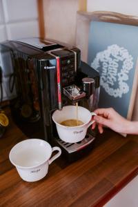 a person is stirring a cup of coffee in a coffee maker at Dom Wypoczynkowy - Alexander in Cisiec