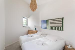 Duas camas brancas num quarto branco com uma fotografia na parede em Residence Iles Bretonnes em Rennes
