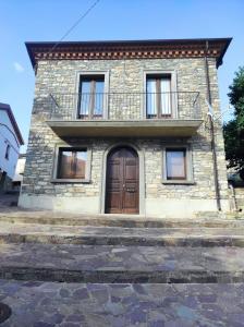 uma casa de pedra com uma varanda e uma porta de madeira em Fantastica casa ai piedi del Monte Pollino em San Lorenzo Bellizzi