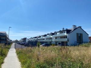 a sidewalk next to a parking lot with buildings at Baltic Apartment Posesja Kapitańska in Grzybowo