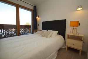 ein Schlafzimmer mit einem weißen Bett und einem Fenster in der Unterkunft Label OR appartement spacieux proximité pistes in Les Deux Alpes
