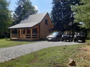 una cabaña de madera con dos ATvs estacionados frente a ella en Domek na Pętli, en Hoczew