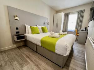 a bedroom with a large bed with green and white pillows at Pearl & Pebbles Eastbourne in Eastbourne