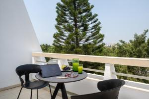 a table with a laptop on a balcony with a tree at Kfar Maccabiah Business & Sport Hotel in Ramat Gan