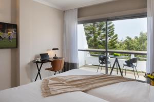 a bedroom with a bed and a large window at Kfar Maccabiah Business & Sport Hotel in Ramat Gan