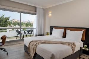 a bedroom with a bed and a large window at Kfar Maccabiah Business & Sport Hotel in Ramat Gan