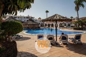 a person sitting in chairs in front of a swimming pool at Apartment Fairways Club in San Miguel de Abona