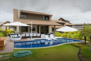 a house with a swimming pool with chairs and umbrellas at Bangalo Malawi em Muro Alto PE in Porto De Galinhas