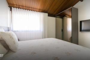 a bedroom with a white bed and a window at Bangalo Malawi em Muro Alto PE in Porto De Galinhas