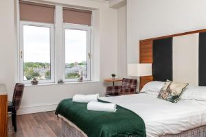 ein Schlafzimmer mit einem Bett mit einer grünen Decke darauf in der Unterkunft Spacious 5-Bedroom Townhouse in the West-End in Aberdeen