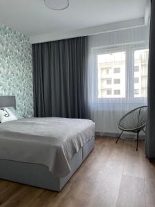 um quarto com uma cama, uma cadeira e uma janela em Apartamenty Termalne na Długiej 8 em Uniejow