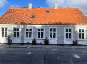 een wit huis met een oranje dak bij Aabels in Sæby