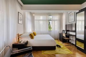 a bedroom with a large white bed and a desk at Theodor Brown Rothschild Tel-Aviv, a member of Brown Hotels in Tel Aviv