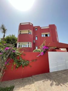 a red building with flowers in front of it at Mehdia Ville in Plage de Mehdia