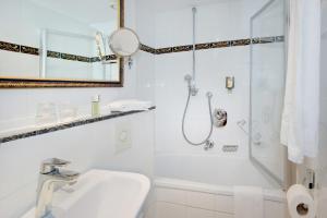 ein weißes Bad mit einer Dusche und einem Waschbecken in der Unterkunft Hotel Aurbacher Hof GmbH in München