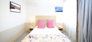 een slaapkamer met een bed met roze kussens bij Trinite Hotel in La Trinité-sur-Mer