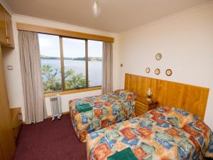 a bedroom with two beds and a large window at Derwent Retreat in Austins Ferry