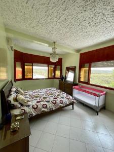 a bedroom with a bed and a desk and windows at Mehdia Ville in Plage de Mehdia