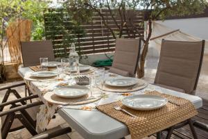 einen Tisch mit Tellern und Gläsern auf einer Terrasse in der Unterkunft Rafia Loft with nice garden right by the beach in Loutraki