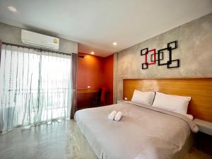 - une chambre avec un grand lit blanc et une fenêtre dans l'établissement B3 Hotel, à Nakhon Si Thammarat
