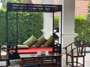 a porch with a bed with pillows and a table at The Old Phuket - Karon Beach Resort - SHA Plus in Karon Beach