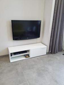TV de pantalla plana en la parte superior de un soporte de TV blanco en Le Plaisance, en Ourville-en-Caux