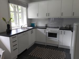una cucina con armadi bianchi, lavandino e piano cottura di Huset i skogen a Moss