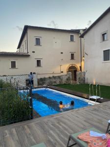 two people in a swimming pool in front of a house at Dimora dell'Arte-CantinArte in Navelli