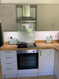 a kitchen with white cabinets and a stove top oven at Stunning 1 bedroom self contained apartment in Kent