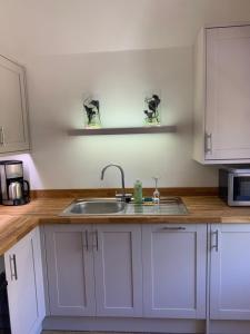a kitchen with white cabinets and a sink at Stunning 1 bedroom self contained apartment in Kent