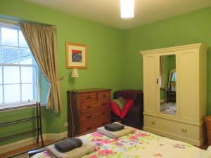 a bedroom with green walls and a bed and a dresser at Anchor House in Pittenweem