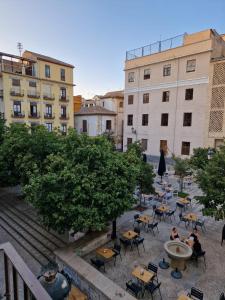 um grupo de mesas e cadeiras num pátio com edifícios em Apartamentos Garam em Granada
