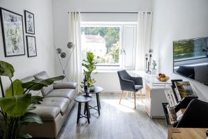 ein Wohnzimmer mit einem Sofa, einem Tisch und einem Fenster in der Unterkunft BONNYSTAY l Modern l Zentral l Work Space l Kitchen l Smart TV l WLAN in Passau